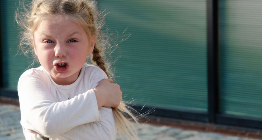 Jeune enfant exprimant une colère visible par sa posture corporelle et son expression faciale, illustrant une émotion normale du développement nécessitant un cadre éducatif contenant