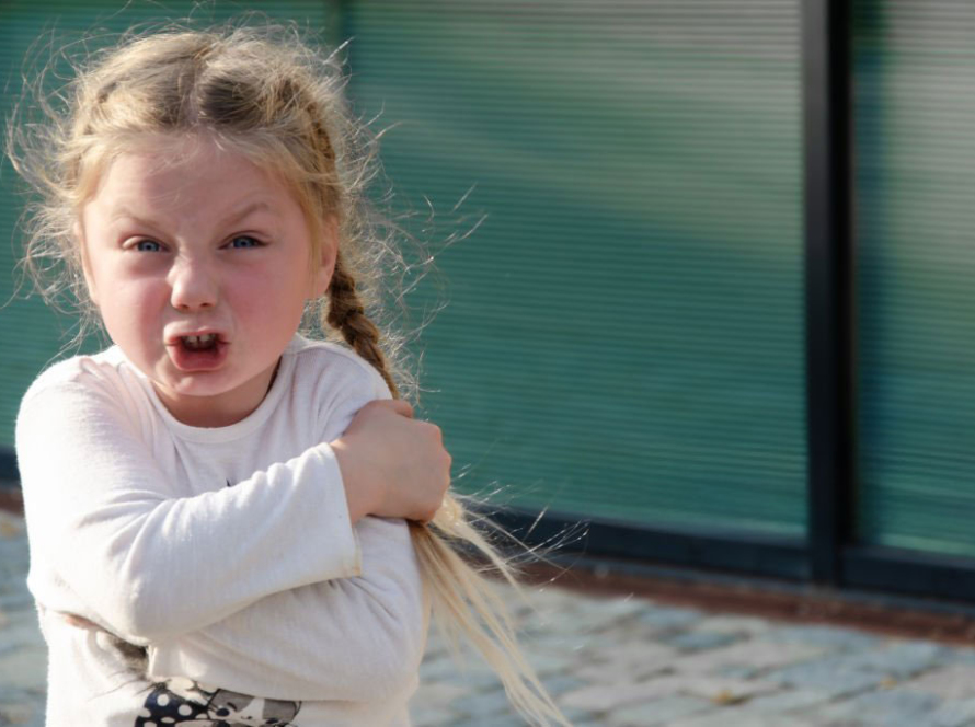 Jeune enfant exprimant une colère visible par sa posture corporelle et son expression faciale, illustrant une émotion normale du développement nécessitant un cadre éducatif contenant