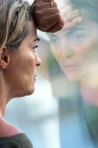 Femme épuisée en introspection devant sa fenêtre