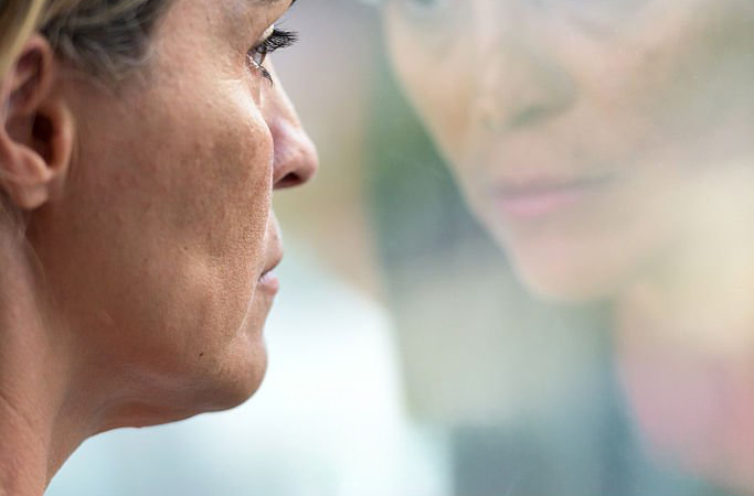 Femme épuisée en introspection devant sa fenêtre