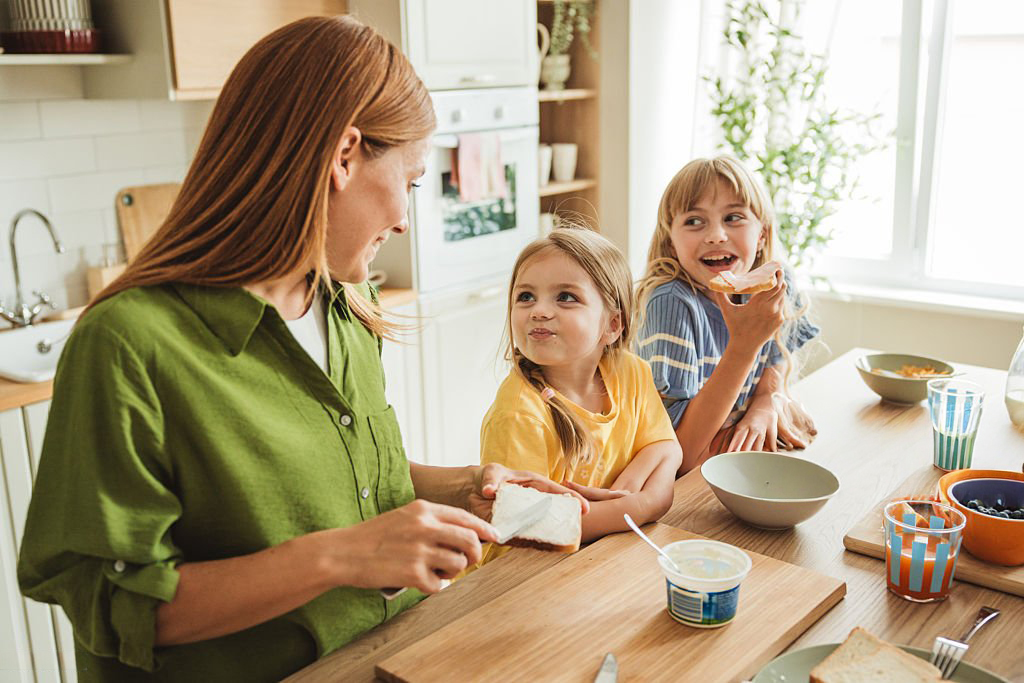 Une maman préparant un petit déjeuner sain pour ses filles dans la bonne humeur et l'harmonie