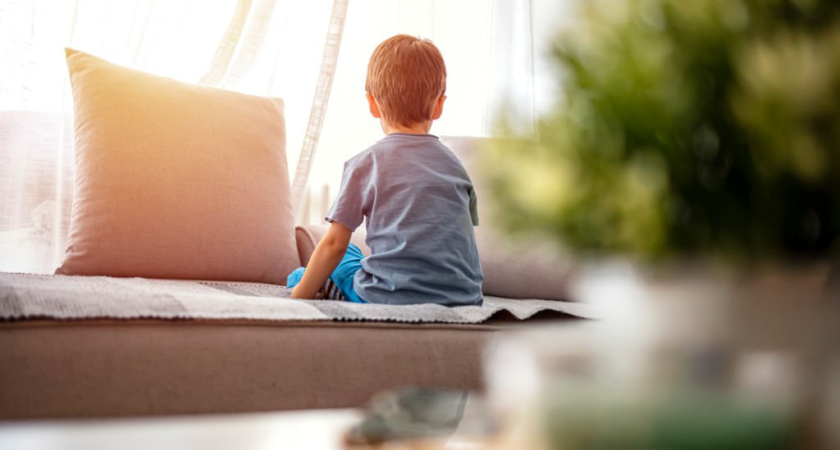 Enfant assis calmement de dos sur un canapé, dans une lumière douce, illustrant un temps de pause éducatif après une colère.