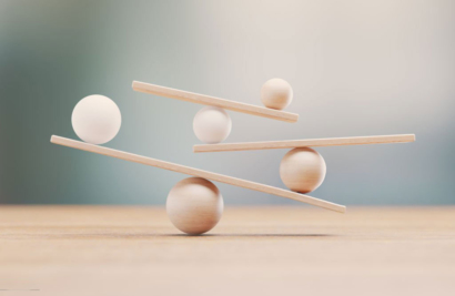 Illustration symbolisant l’équilibre entre bienveillance et cadre éducatif, avec des formes en bois en équilibre instable représentant les ajustements nécessaires en éducation.