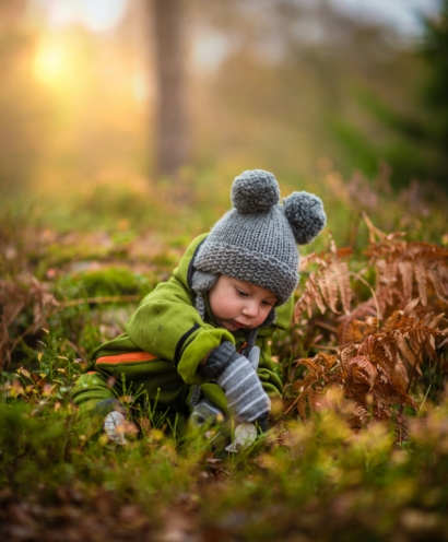Jeune enfant explorant calmement son environnement naturel, illustrant la sécurité, le cadre et les besoins éducatifs fondamentaux du développement de l’enfant.